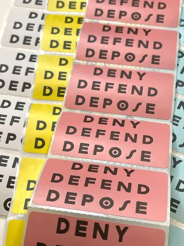 Assorted rectangular stickers in pink, yellow, white, and blue, each printed with 'DENY DEFEND DEPOSE.'