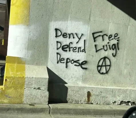 Black graffiti on a concrete wall reading 'Deny Defend Depose' beside 'Free Luigi' and a circled-A symbol.